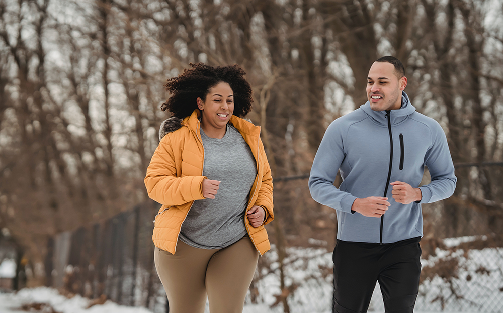 An overweight woman running with a man outside in the winter