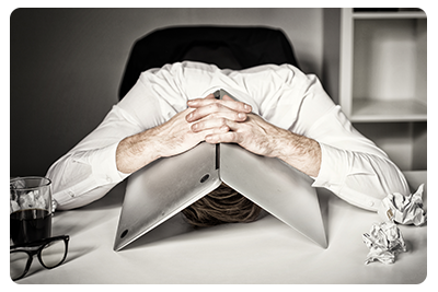 A man in an office with his head under his open laptop
