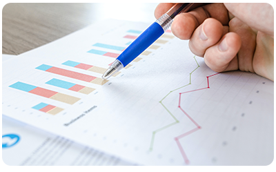 A person holding a pen on a piece of paper showing metrics