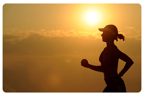 A woman jogging outdoors at sunrise